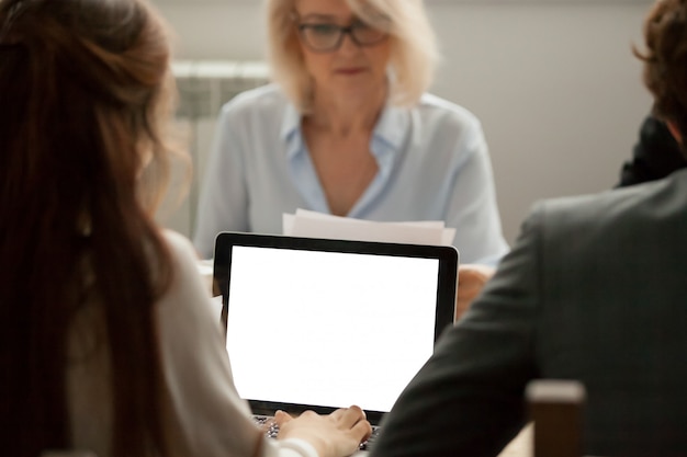 Gerente de sexo femenino que trabaja con estadísticas del proyecto en la computadora portátil en la reunión