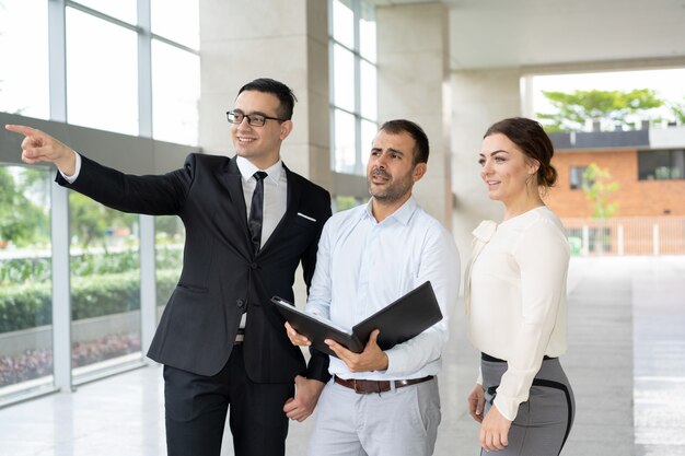 Gerente sonriente que muestra el objeto inmobiliario a los inversores