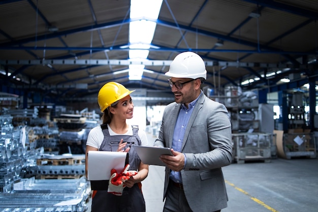 Gerente supervisor y trabajador discutiendo sobre los resultados de producción y la nueva estrategia en la nave industrial de la fábrica