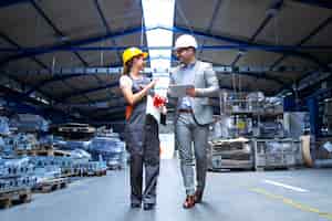 Foto gratuita gerente supervisor y trabajador industrial en uniforme caminando en la gran sala de la fábrica de metal y hablando de aumentar la producción