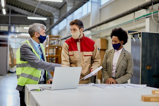 Gerentes de empresas de carpintería comunicándose con trabajadores masculinos en instalaciones de producción