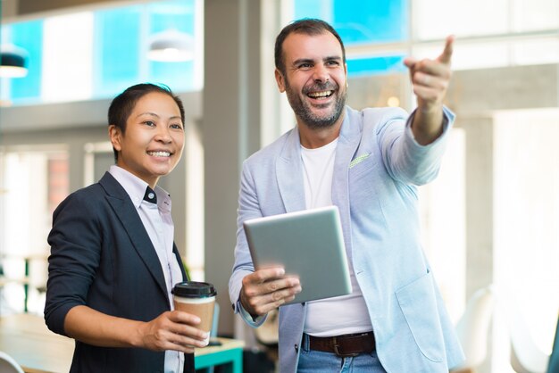 Gerentes positivos latinos y asiáticos tomando un café en la oficina