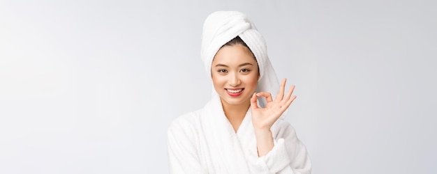 Gesto aceptable de la mujer asiática de la belleza para el buen producto facial aislado en el concepto de la belleza y de la moda del fondo blanco