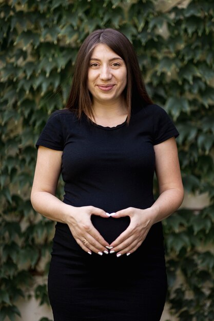 Gesto de mano en forma de corazón de mujer embarazada