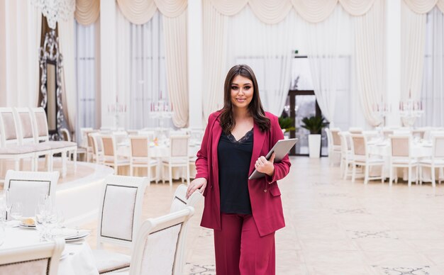 Gestor de eventos con laptop en salón de banquetes.