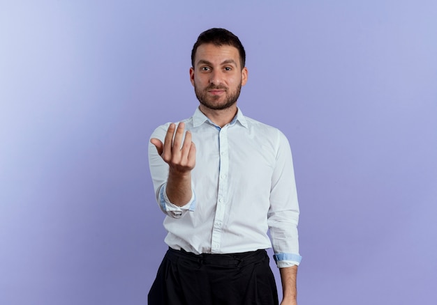 Gestos de hombre guapo confiado vienen aquí signo de mano aislado en la pared púrpura