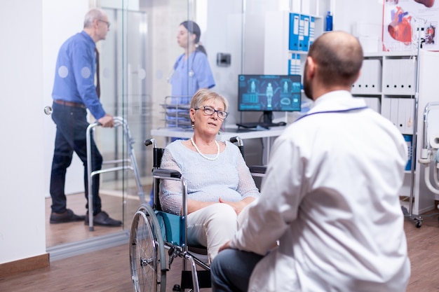 Giatra consulta mujer inválida en silla de ruedas en la sala de examen del hospital