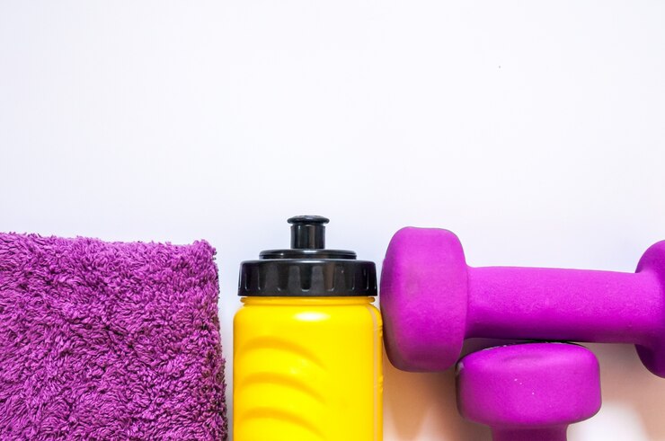 Gimnasio equipos de gimnasio. Pesas con la toalla y el embotellador del wate. Calzado de entrenamiento. Entrenadores deportivos sobre fondo blanco. Deporte, estilo de vida saludable y objetos concepto