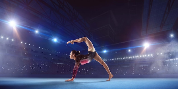 Gimnasta femenina haciendo un truco complicado en la barra de equilibrio de gimnasia en un campo profesional