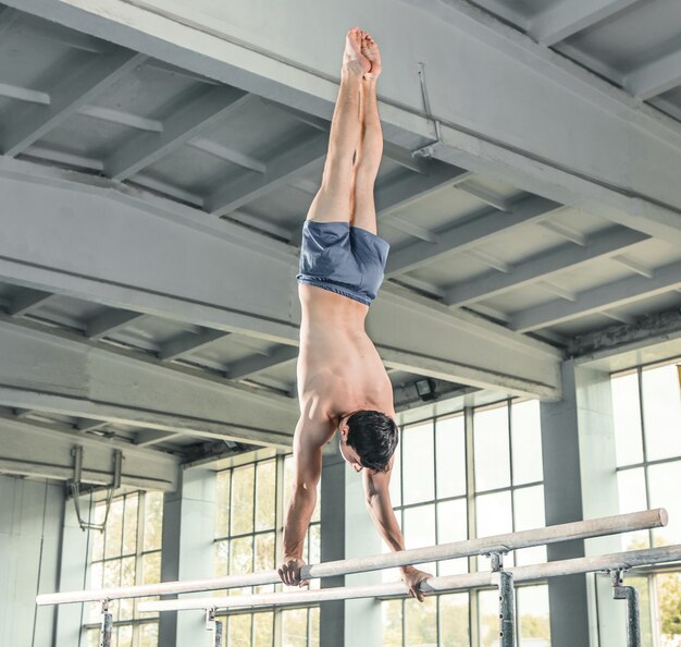 Gimnasta masculino realizando parada de manos en barras paralelas