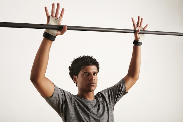 Foto gratuita gimnasta negra de aspecto serio en camiseta gris y protección de manos de gimnasia preparándose para agarrar una barra de dominadas de carbono negro, dedos extendidos, aislado en blanco