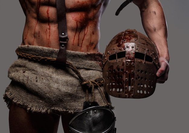 Gladiador con cuerpo musculoso sosteniendo un casco