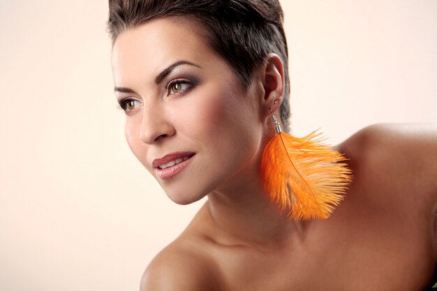 Glamour y preciosa morena con aretes de plumas