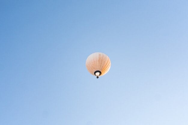 Globo de aire caliente amarillo volando en el cielo azul claro