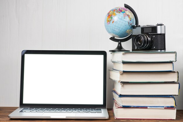 Globo y cámara en libros cerca de la computadora portátil