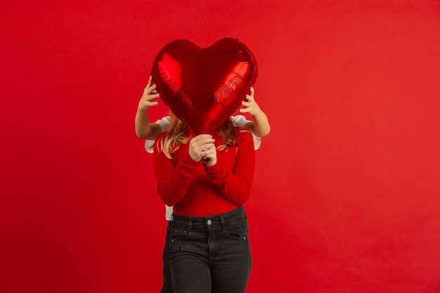 Foto gratuita globo en forma de corazón frente a la cara de una niña.