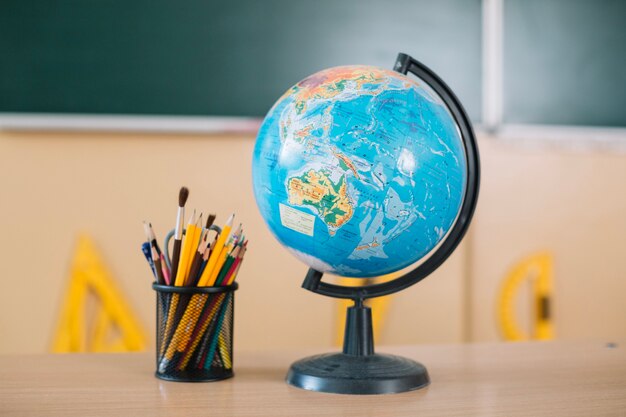 Globo y herramientas de escritura en la mesa de la escuela