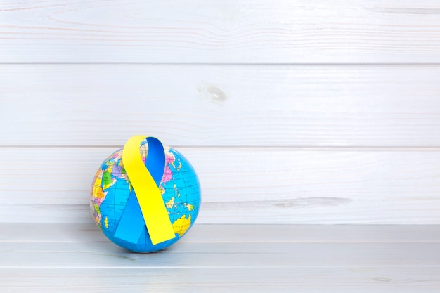 Globo del mundo con cinta amarilla y azul sobre fondo de madera. concepto del día mundial del síndrome de down. espacio para texto.