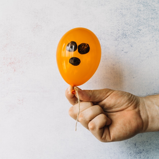 Globo naranja con cara pintada de negro