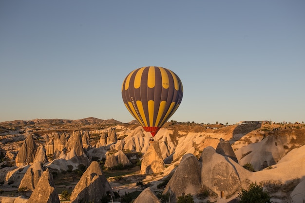 Globos de aire caliente sobre las colinas y los campos durante la puesta de sol en Capadocia, Turquía