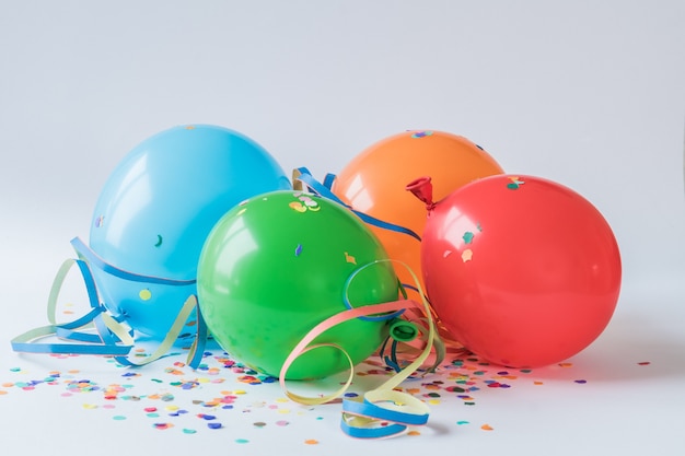 Globos de colores en los confettis de papel sobre una superficie blanca