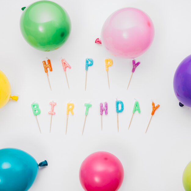 Globos coloridos alrededor de las velas del feliz cumpleaños aisladas en el fondo blanco