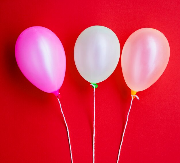 Globos de fiesta de cumpleaños sobre fondo rojo.