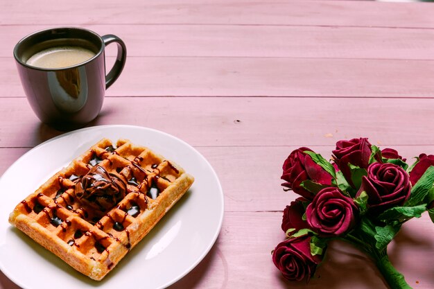 Foto gratuita gofre belga con ramo de rosas y taza de café