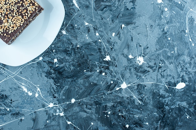 Gofre recubierto de chocolate en un plato, sobre la mesa azul.