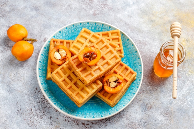 Gofres belgas cuadrados con frutas de níspero y miel.