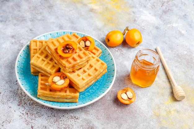 Gofres belgas cuadrados con frutas de níspero y miel.