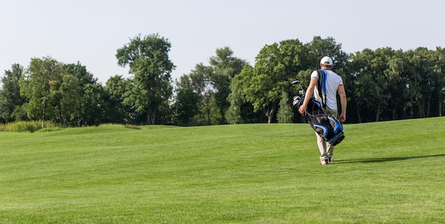 Golfista con bolsa de golf caminando por el campo