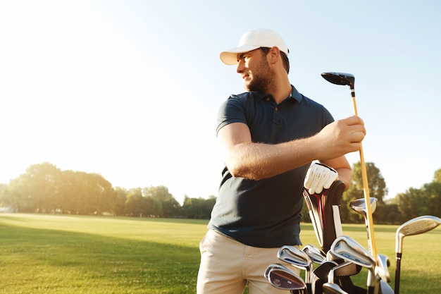 Golfista hombre sacando el club de golf de una bolsa