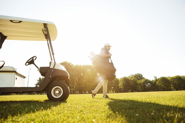 Golfista masculino caminando con bolsa de golf