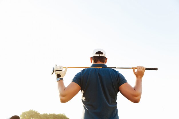 Golfista masculino con conductor mientras está de pie en curso verde