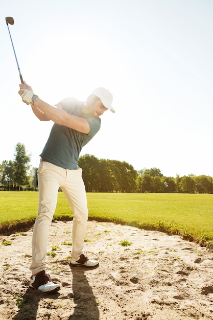 Foto gratuita golfista a punto de golpear la pelota fuera de un búnker de arena