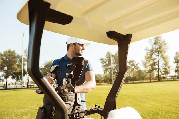 Golfista sacando palos de una bolsa en un carrito de golf