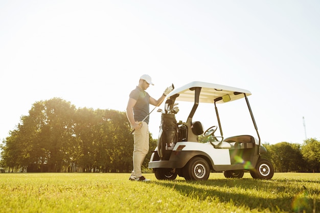 Golfista sacando palos de una bolsa en un carrito de golf