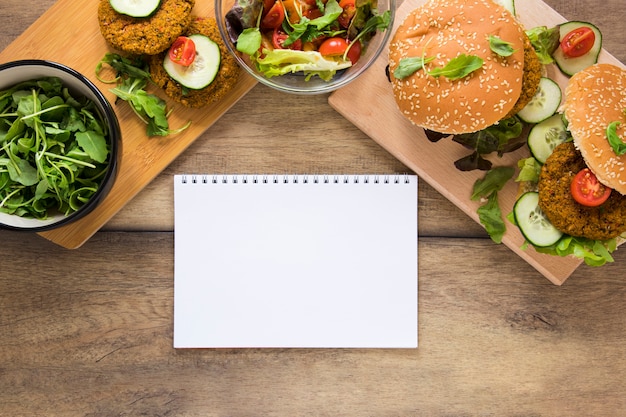 Foto gratuita golosinas veganas junto al cuaderno vacío en la mesa de madera