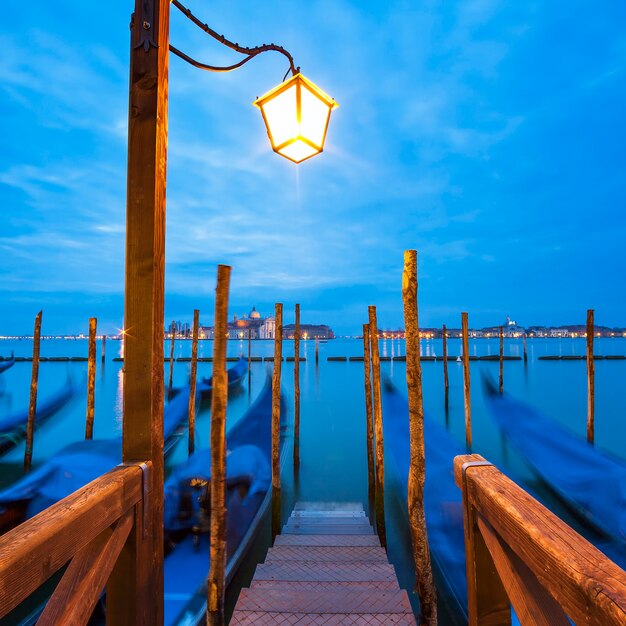 Las góndolas amarradas por la plaza San Marcos con la iglesia de San Giorgio di Maggiore en el espacio - Venecia, Venecia, Italia, Europa