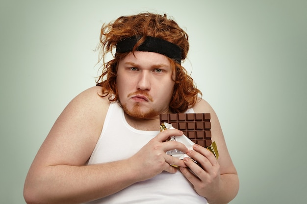 Gordo gordo obeso codicioso vistiendo una banda deportiva en el pelo rizado de jengibre