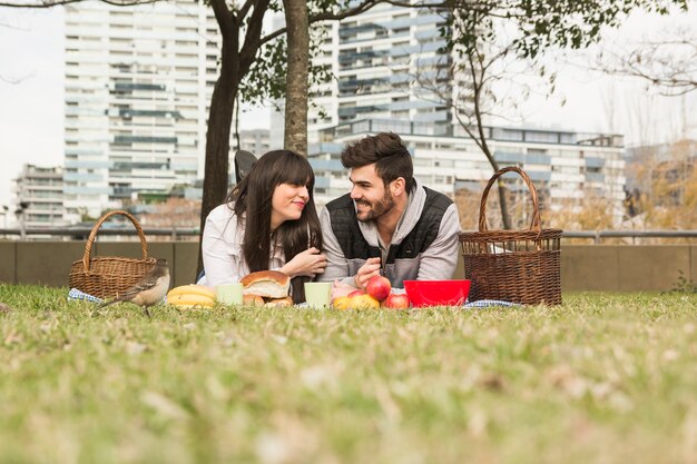 Gorrión delante de la joven pareja disfrutando en el picnic en el parque