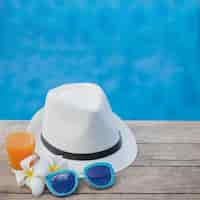 Foto gratuita gorro, gafas de sol y bebida con piscina de fondo