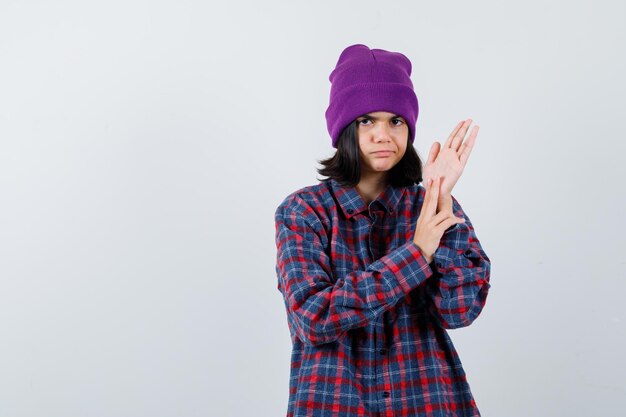 Gorro de mujer pequeña frotando las palmas de las manos mirando serio