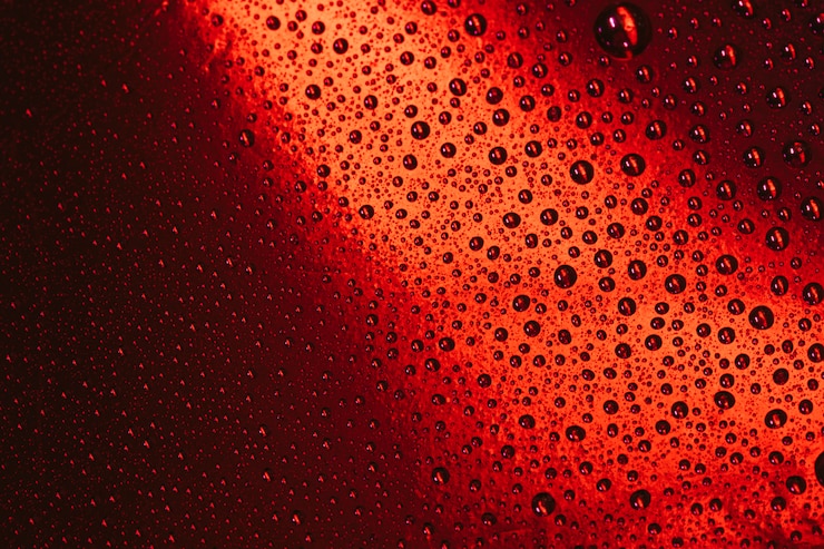 Foto gratuito gotas de agua en un fondo rojo brillante de vidrio