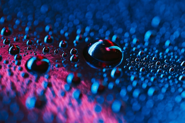 Gotas de agua sobre fondo azul y rosa brillante de vidrio