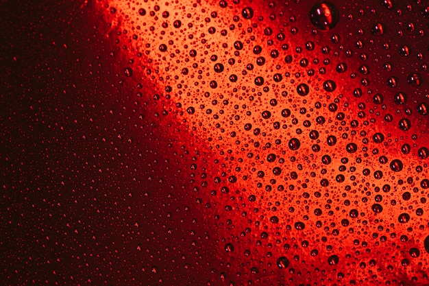 Gotas de agua sobre fondo brillante de cristal rojo