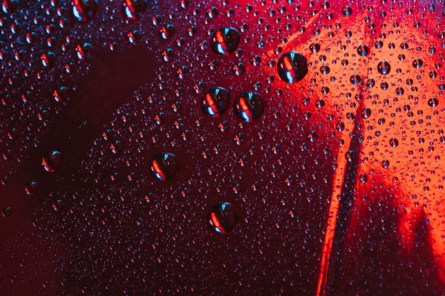 Gotas de agua sobre el vidrio reflectante rojo