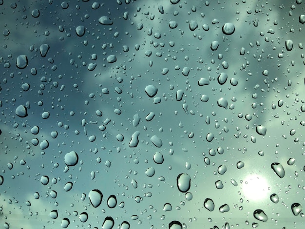 Gotas de lluvia en una ventana con un cielo azul