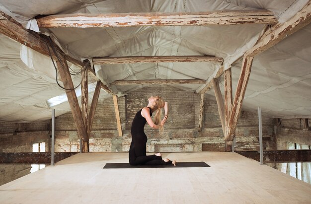 Gracia. Una joven atlética ejercita yoga en un edificio de construcción abandonado. Equilibrio de salud mental y física. Concepto de estilo de vida saludable, deporte, actividad, pérdida de peso, concentración.